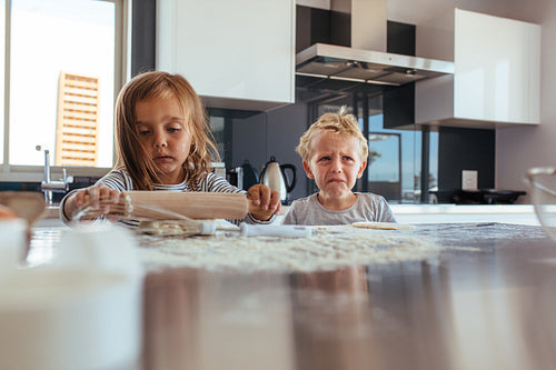 Little girl making cookies and boy crying in kitchen