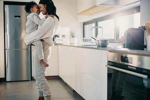 Single mother carrying her daughter in the kitchen