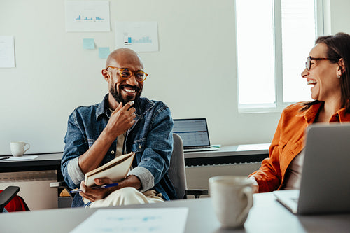 Meeting in an office with laughing employees bonding over shared ideas