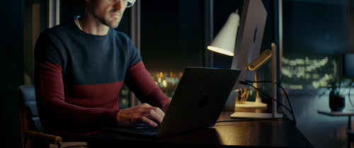 Young man working late on laptop in city apartment