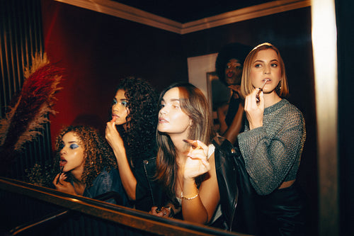 Friends enjoying a night out and applying makeup in the ladies' room