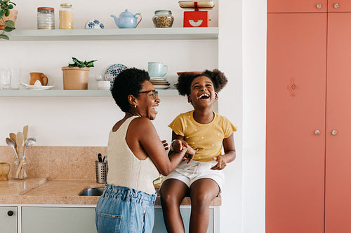 Happy mother and daughter sharing laughter and playfulness in the kitchen