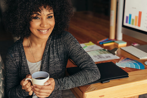 Happy woman having coffee at home office desk