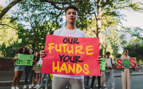 Teenage boy holding a banner sign during a climate change demonstration