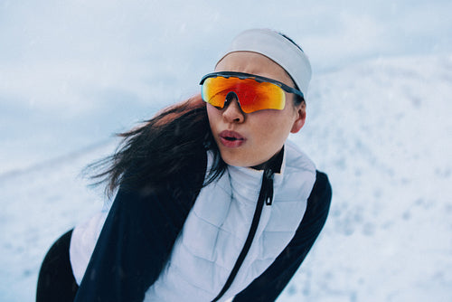 Running woman pauses in winter snow to recover during outdoor training