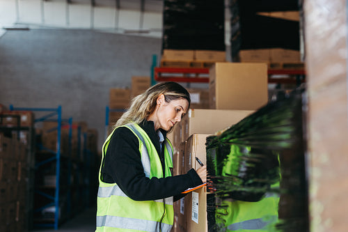 Warehouse supervisor writing on a clipboard in a logistics centre