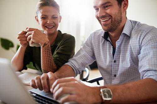 Smiling couple at home using laptop