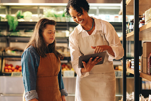 Happy grocery store supervisor using a digital tablet with her employee