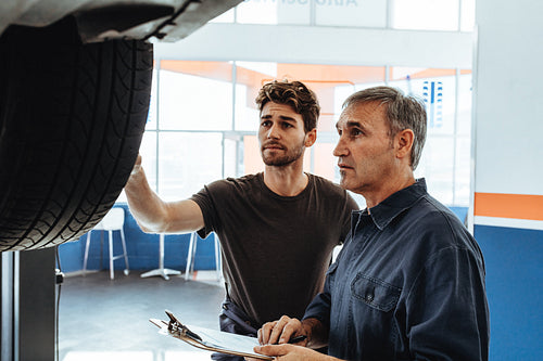 Mechanics examining the car and making notes in service station