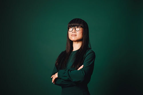 Business portrait of confident Asian woman with glasses in studio