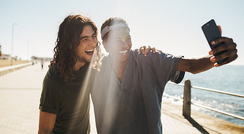 Cheerful friends making a selfie on a seaside promenade