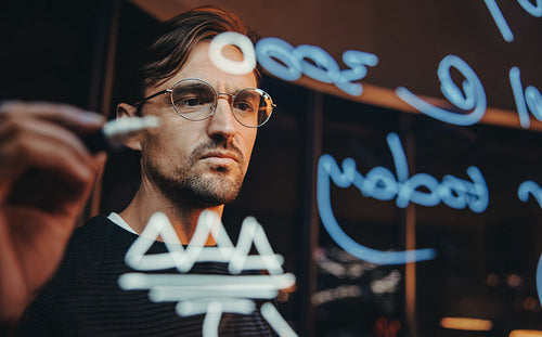 Late night brainstorming: Data analyst working on a glass wall in his office