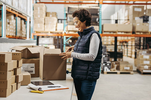 Happy warehouse manager packing a cardboard box