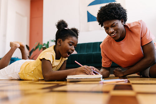 Big brother helping his little sister with her colouring homework