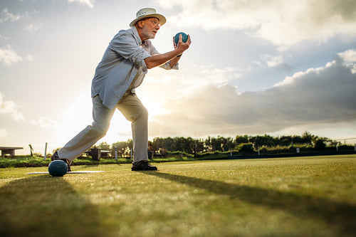 Side view of an elderly man playing boules
