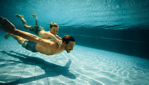 Father and son enjoying underwater swimming in pool