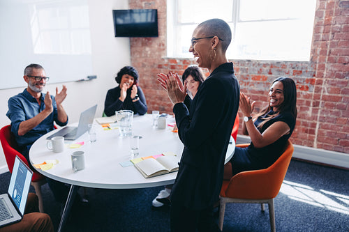 Happy young businesswoman receiving praise from her team in an o