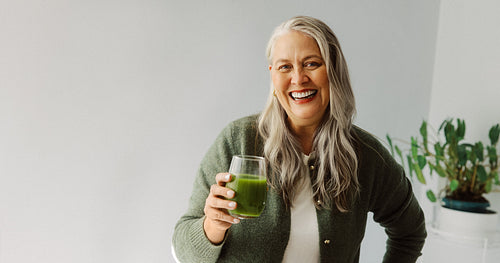 Senior woman holds green smoothie for healthy nutrition