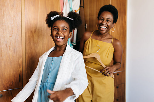Fun with mom's closet: Girl and her mom sharing a fun fashion moment in the bedroom