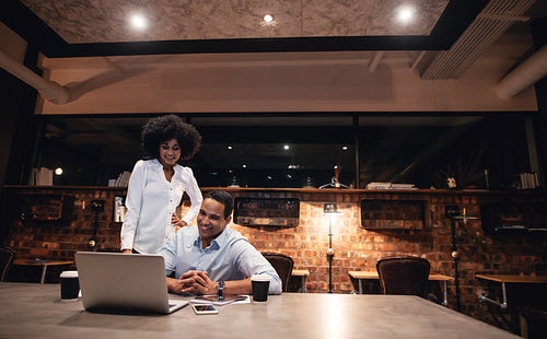 Happy business people working together late in office