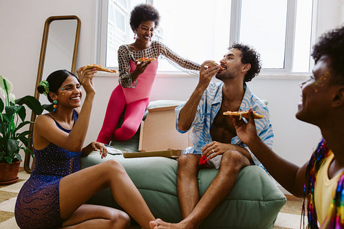 Friends eat pizza at a lively home party