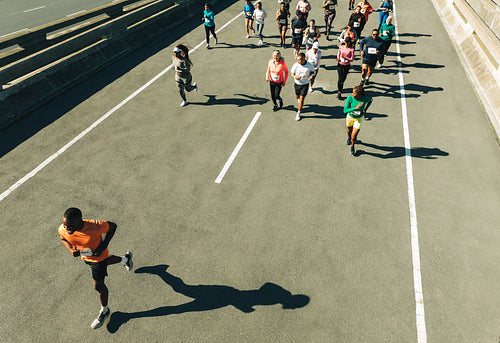 Male runner leading a group marathon on city street