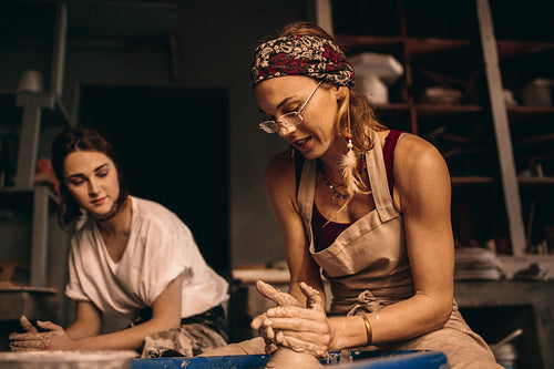 Two women at a pottery workshop making clay pots