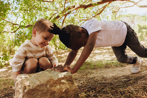 Two children exploring nature together in a green outdoor setting