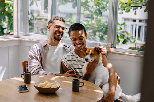 Happy couple enjoying quality time with their dog by the window
