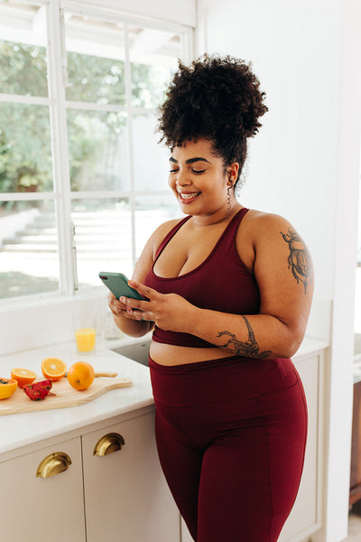Healthy woman checking cell phone in kitchen