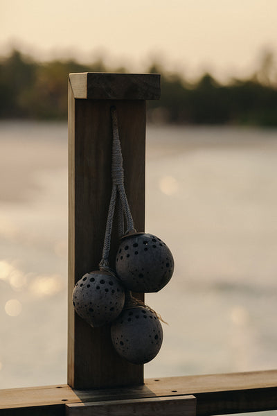 Wooden deck post with round hanging ornaments at sunrise on a tropical island