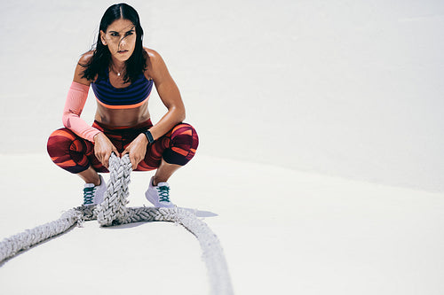Fitness woman relaxing after workout holding battle ropes