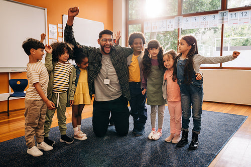 Primary school teacher celebrating with his students in a classroom