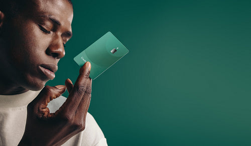 Black man holding out a green credit card in a studio