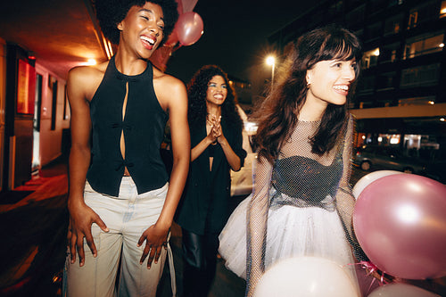 Three friends laughing and enjoying a night out holding balloons