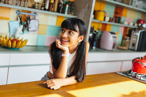 Smiling girl in colorful kitchen leaning on wooden countertop