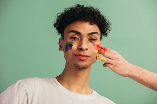 Gay man getting pride flag painted on his face
