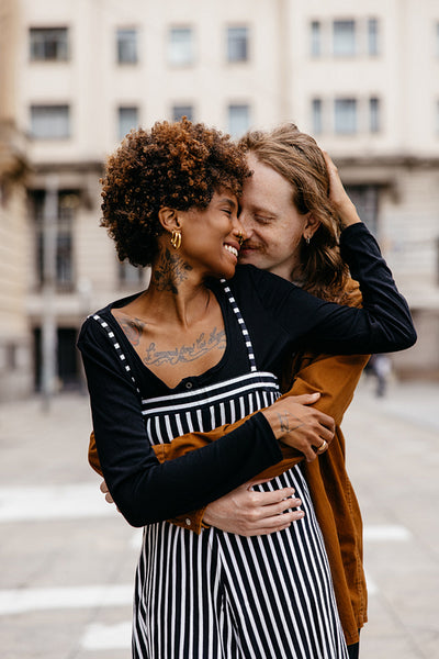 Affectionate embrace on city streets, diverse couple smiling