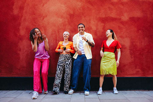 Joyful friends laughing in vibrant urban setting against red wall