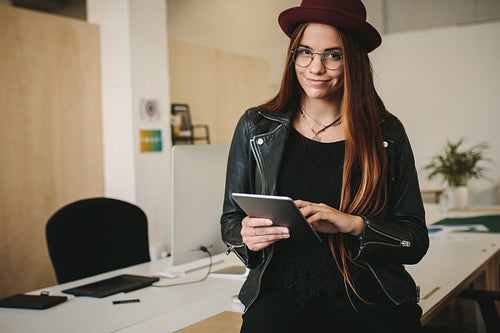 Creative businesswoman standing in office holding tablet pc
