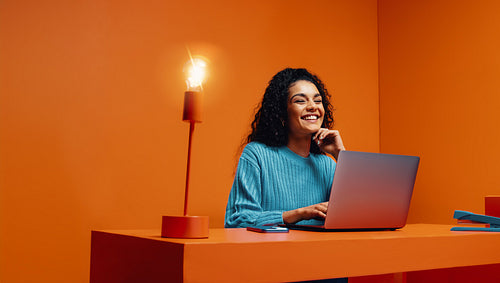 Happy woman sitting at desk with light bulb , thinking of creative ideas.