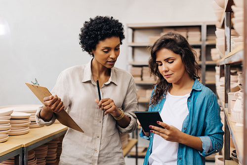 Two female ceramists working together in their store