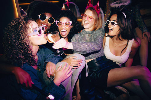 Group of friends enjoying a party while sharing drinks and smiling