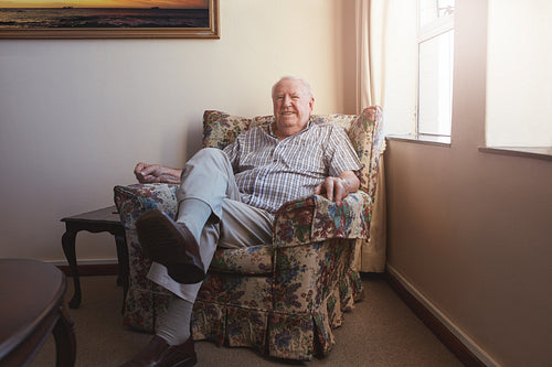 Relaxed elderly man sitting on a arm chair