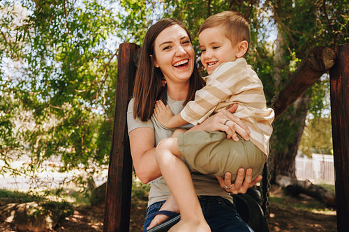 Mother and young son laughing together outdoors in a park setting