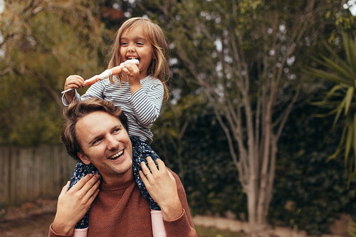 Little girl with her father outdoors holding a candy 