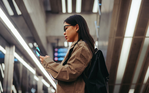 Woman using phone while waiting in subway station