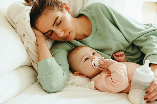 New mom taking a nap next to her baby