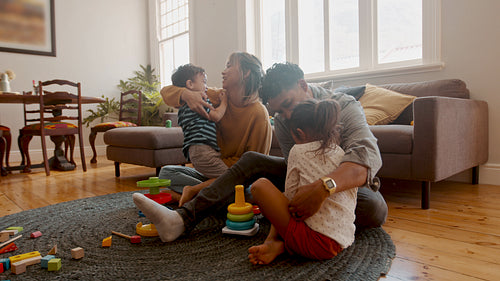 Mom and dad having some family fun with their kids at home, playing together indoors