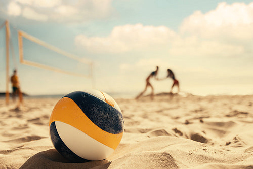 Pro women's beach volleyball players in championship match on coastal sand court at sunset
